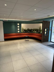 Salle avec carrelage blanc, ainsi que des bancs et mur vert