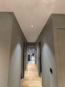 Couloir éclairé montrant l'intérieur d'un bâtiment, avec murs gris